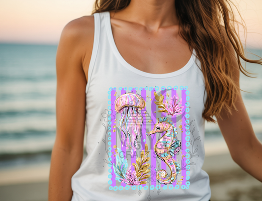 Person wearing a white tank top with a colorful jellyfish and seahorse design on a beach.