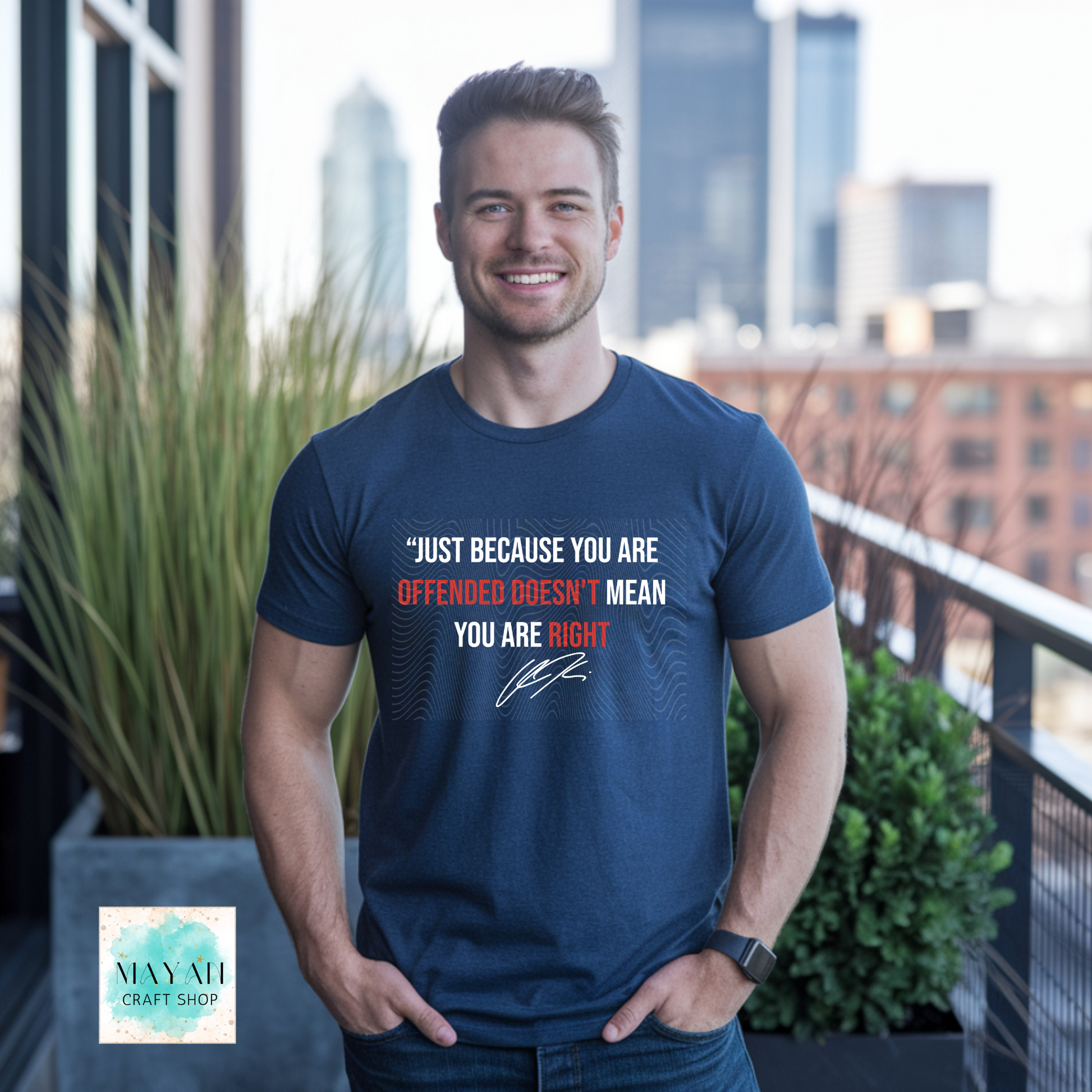 Man wearing a blue t-shirt with a message, standing on a balcony with cityscape in the background