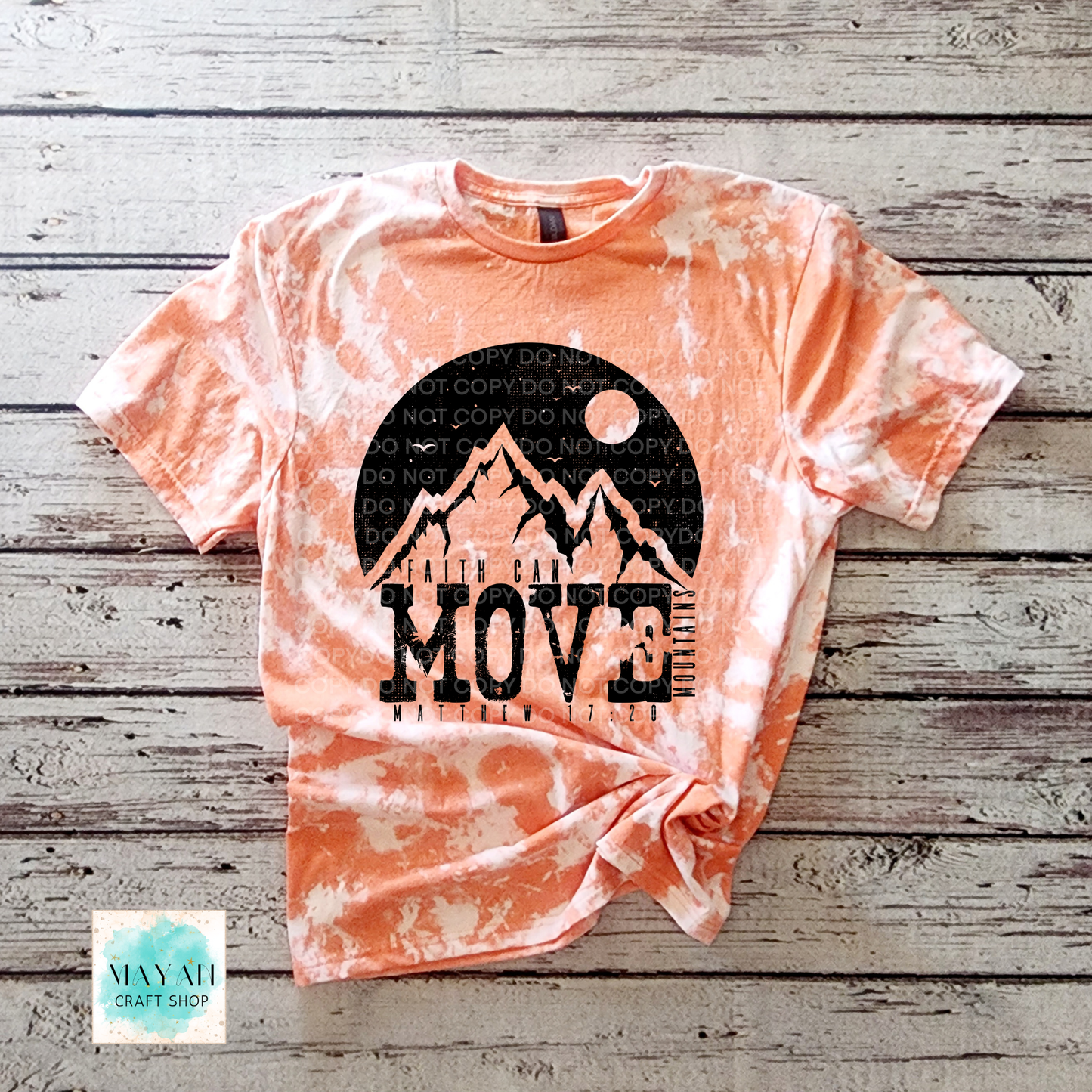 Tie-dye t-shirt with mountain graphic and 'MOVE' text on a wooden surface