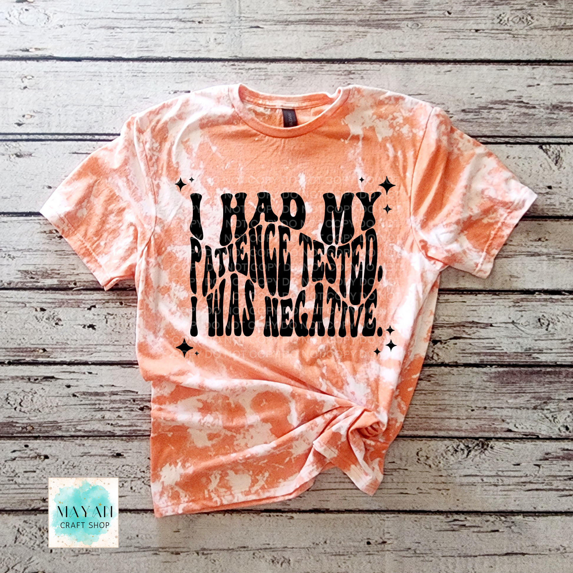 Tie-dye t-shirt with text on a wooden surface, featuring the brand 'Mayan Craft Shop'.