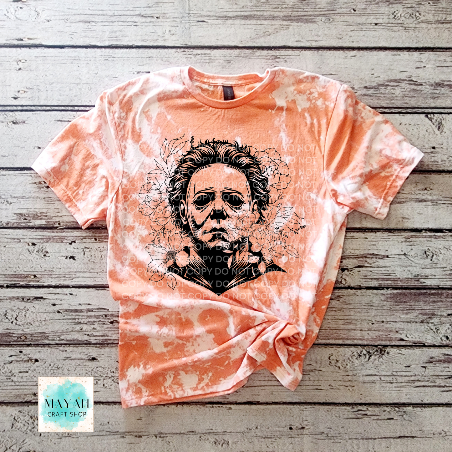 Orange bleached t-shirt with black graphic design on a wooden surface.