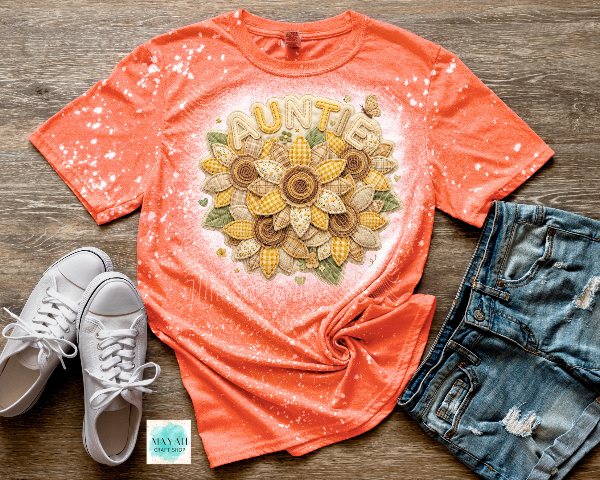 Coral t-shirt with 'Auntie' and cornflower design, paired with white sneakers and denim shorts on a wooden surface.