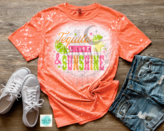 Orange t-shirt with 'Tequila Lime & Sunshine' design, white sneakers, and denim shorts on a wooden surface.