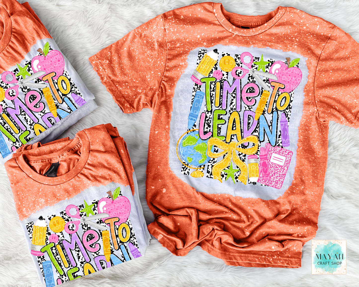 Three orange short-sleeve graphic T-shirts arranged on a white faux-fur surface. The shirts feature a colorful school-themed print with the words “Time To Learn,” apples, pencils, a globe, and a notebook.