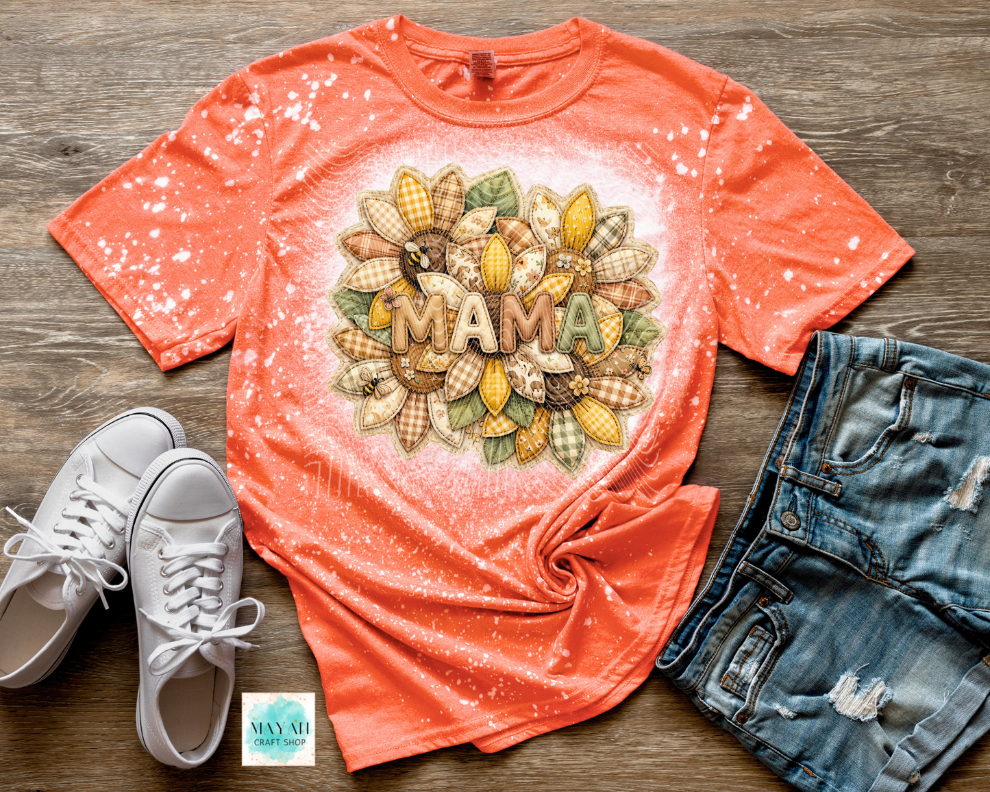 Coral t-shirt with 'MAMA' design on a wooden surface with white sneakers and denim shorts.