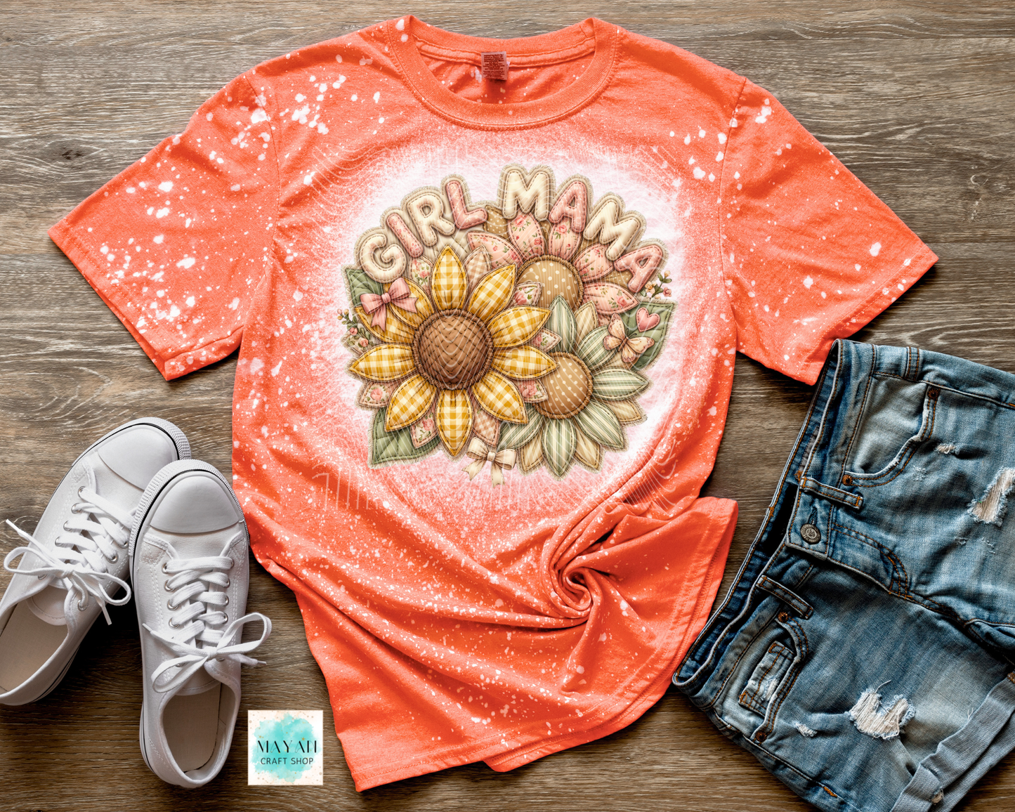 Coral t-shirt with 'Girl Mama' graphic design on a wooden surface with white sneakers and denim shorts.