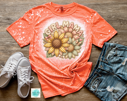 Coral t-shirt with 'Girl Mama' graphic design on a wooden surface with white sneakers and denim shorts.