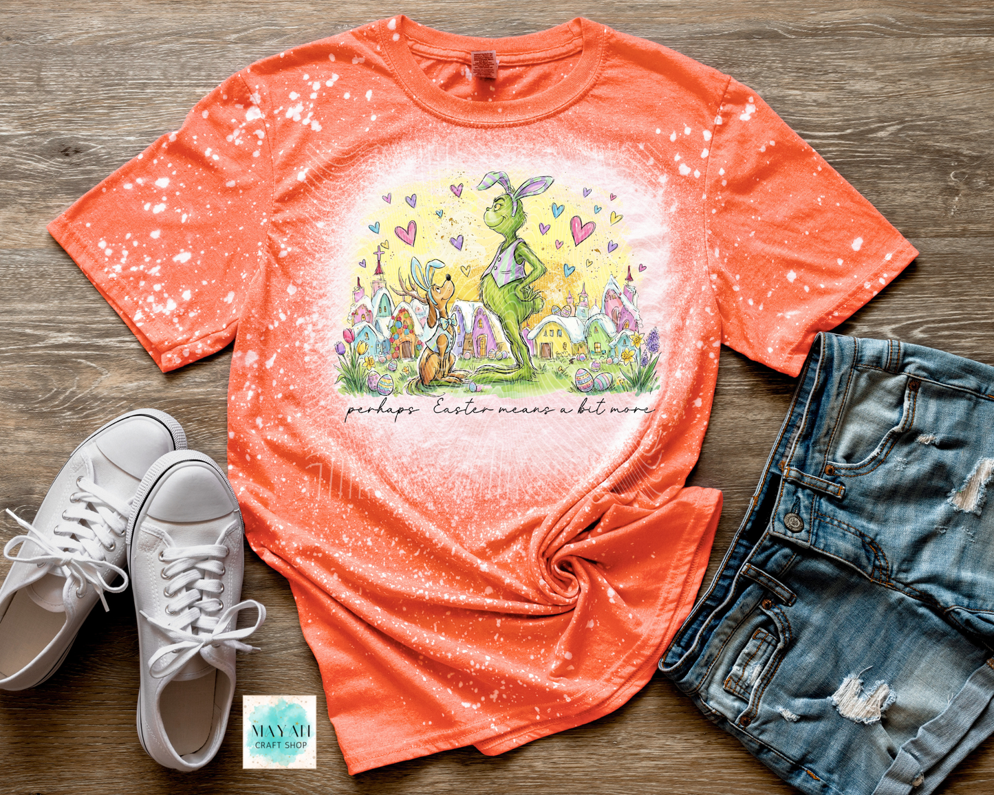 Orange t-shirt with Easter graphic design on a wooden surface with sneakers and shorts.