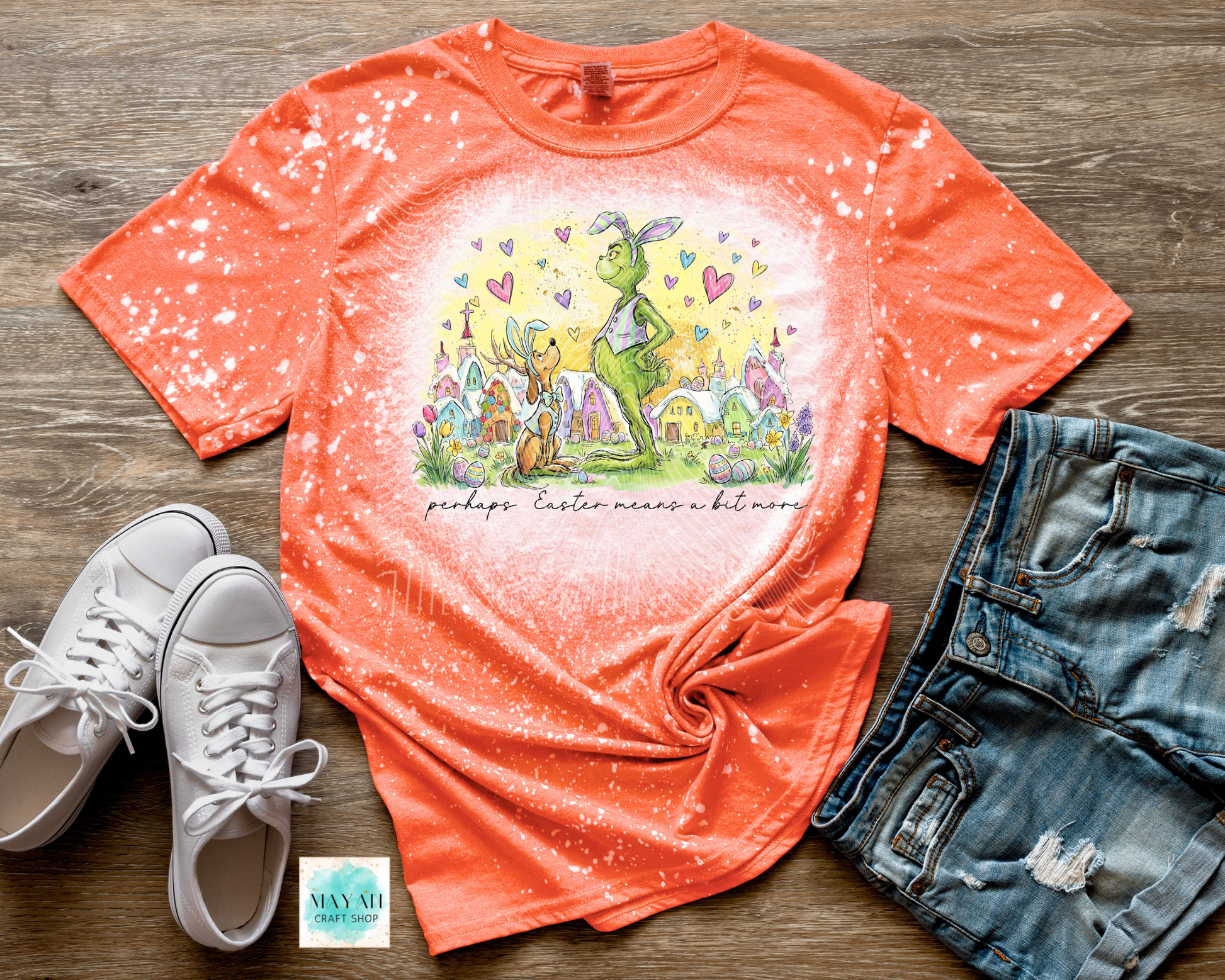 Orange t-shirt with Easter graphic design on a wooden surface with sneakers and shorts.