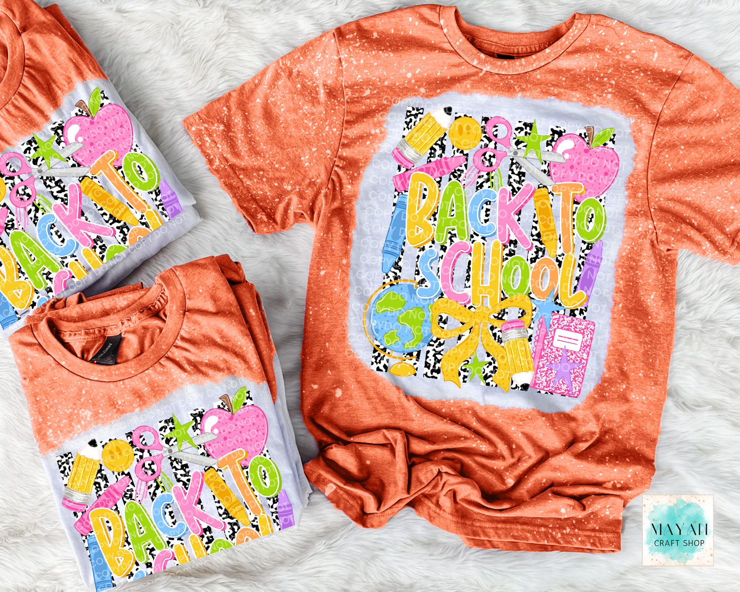 Three orange short-sleeve t-shirts with a colorful 'Back to School' graphic, displayed in different sizes on a white faux fur background. The graphic features school-themed illustrations like apples, and a notebook in bright colors.
