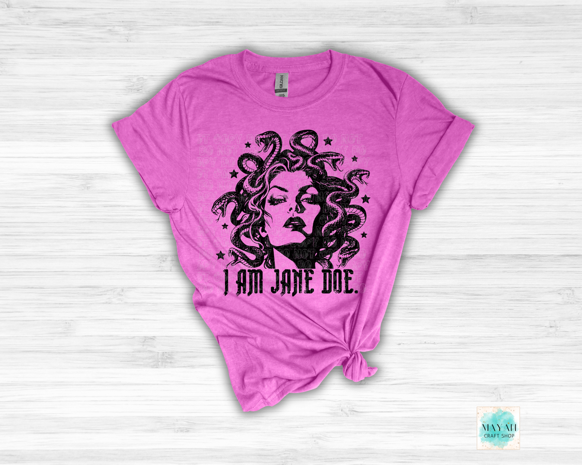 A heather orchid short-sleeve t-shirt with a black graphic of Medusa's face and snakes wrapped around her hair, with the text 'I AM JANE DOE.' printed below.