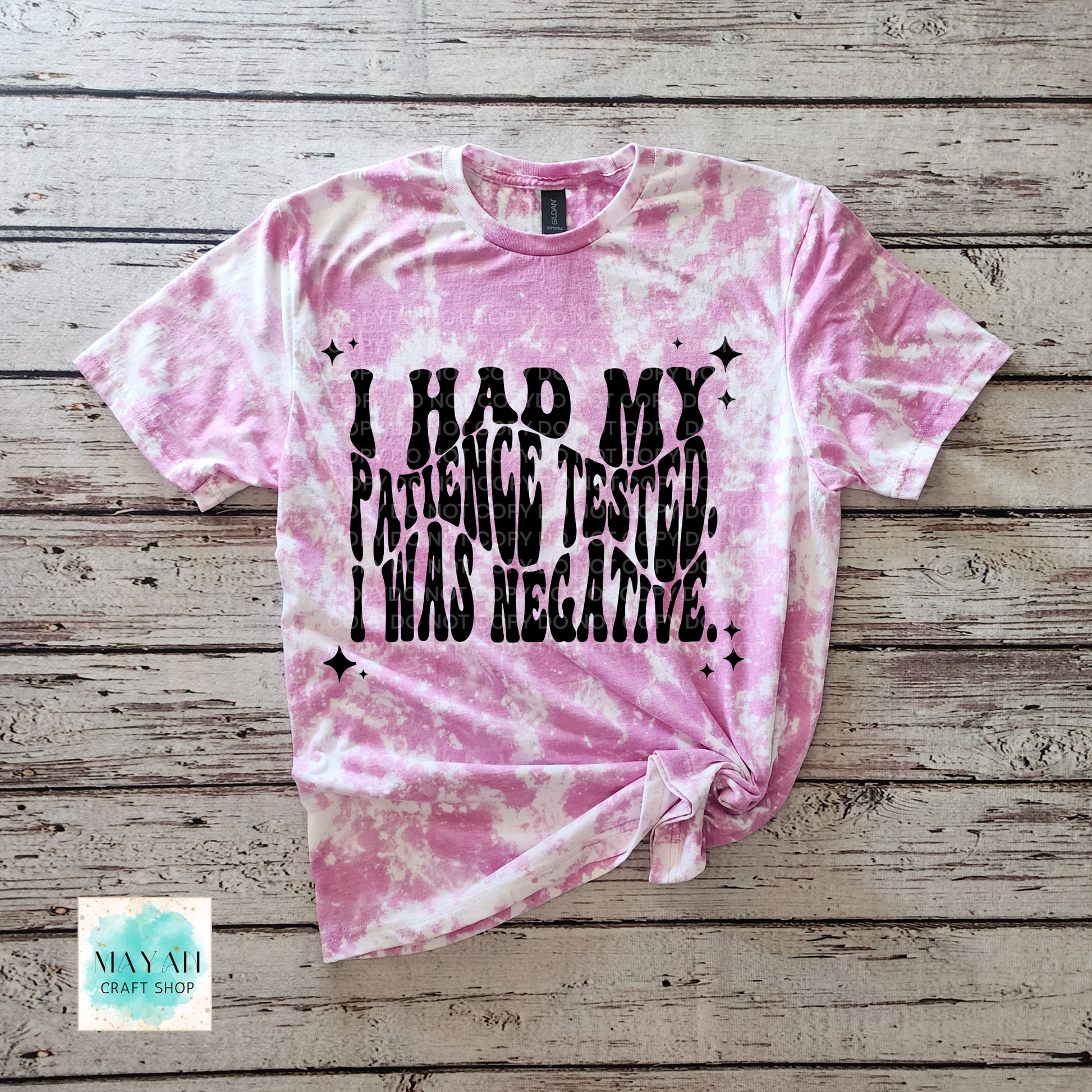 Pink tie-dye t-shirt with text on a wooden surface, featuring the brand 'Mayan Craft Shop'.