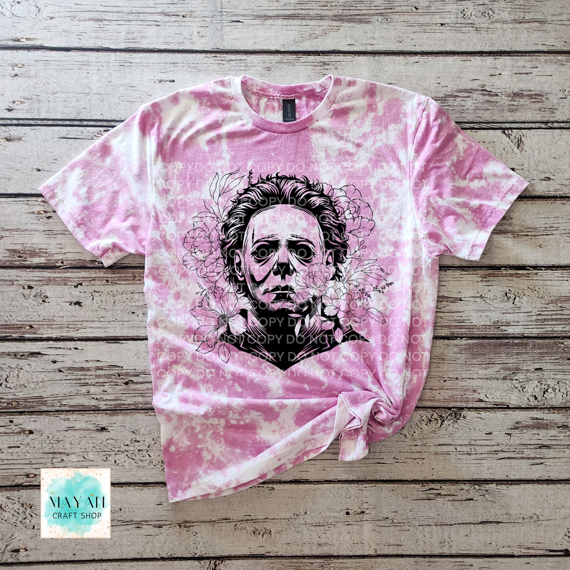 Orchid bleached t-shirt with a graphic design on a wooden surface.