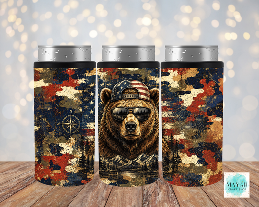 Three cylindrical can coolers with a bear design featuring an American flag and camouflage pattern on a wooden surface.