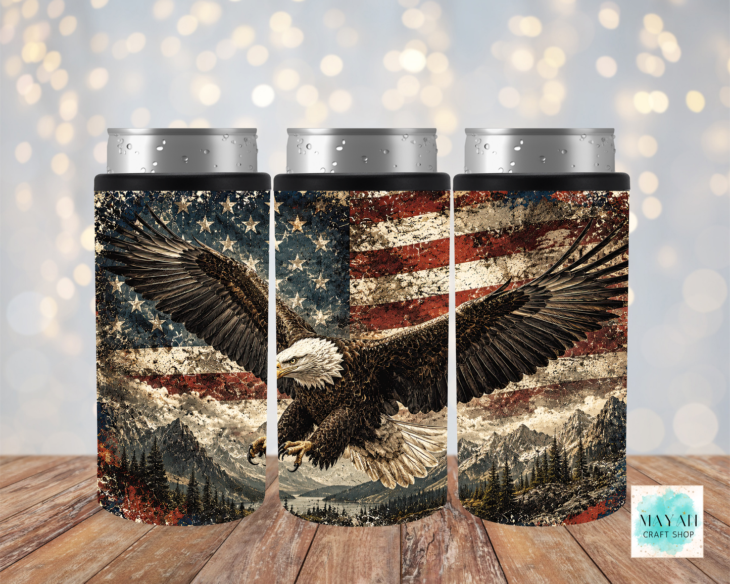 Three cylindrical can coolers with an American flag and bald eagle design on a wooden surface.
