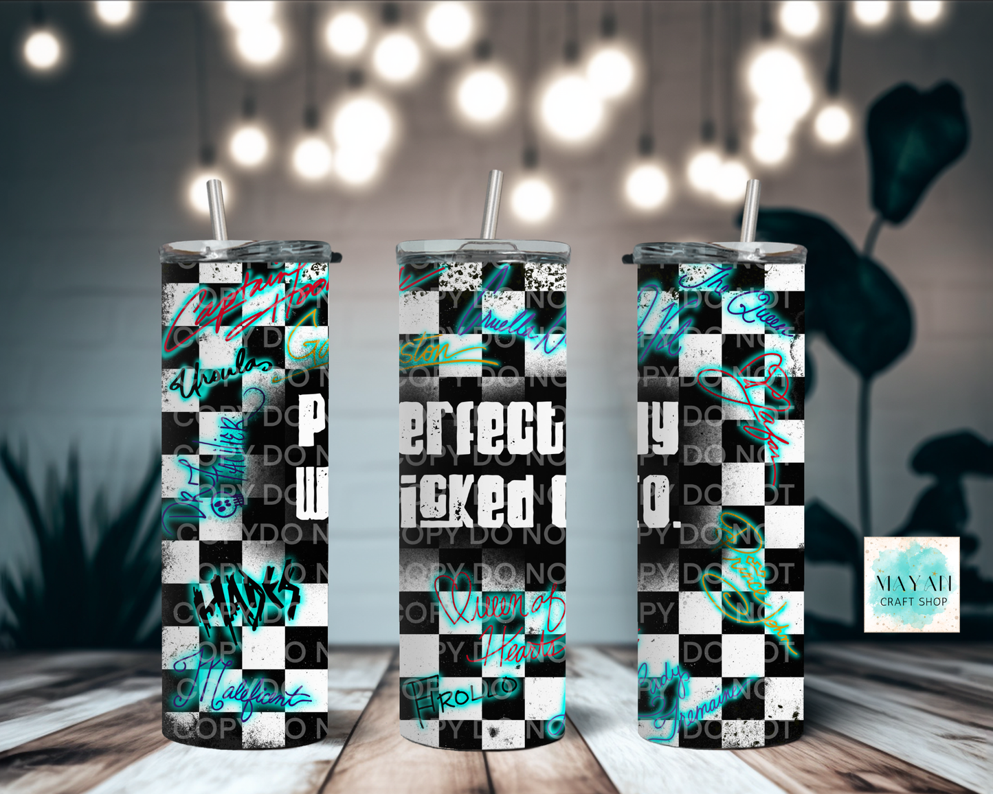 Three tumblers with checkered pattern and text on a wooden surface with blurred lights in the background.
