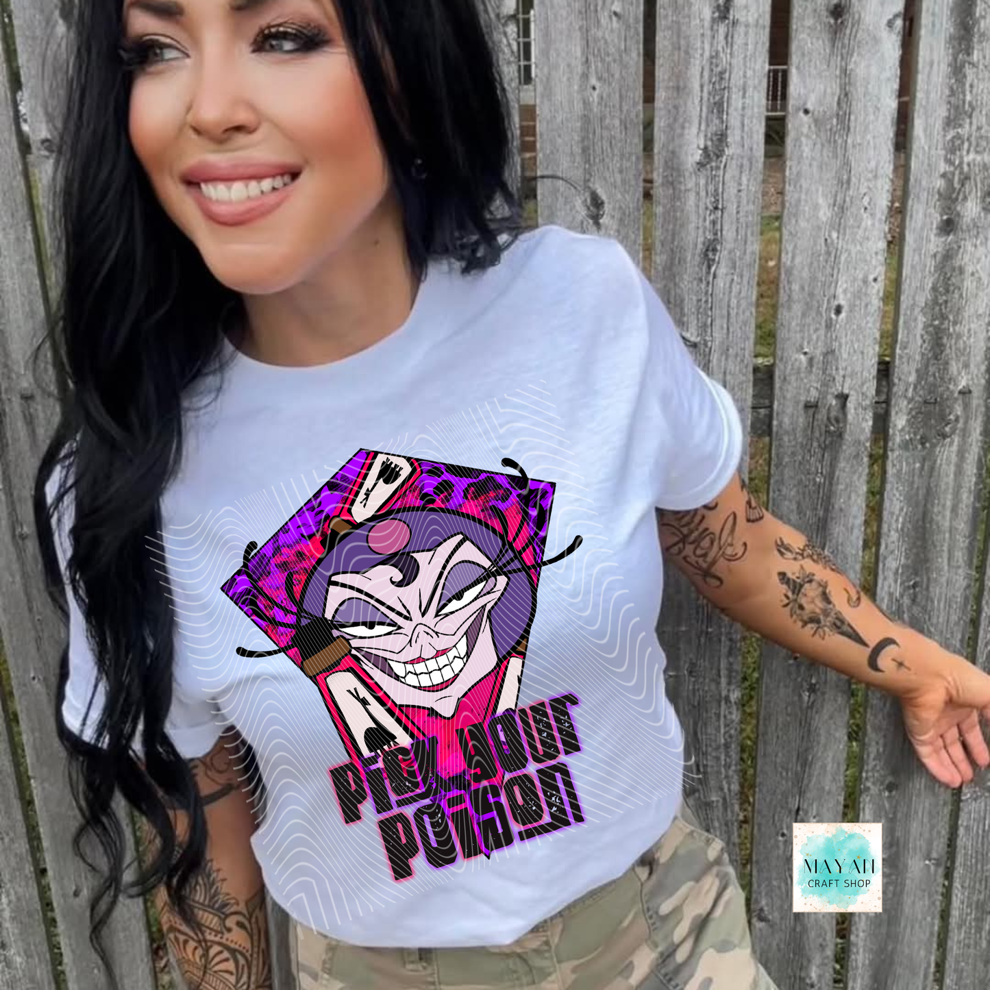 Person wearing a white t-shirt with a cartoon character design and text, standing against a wooden fence.