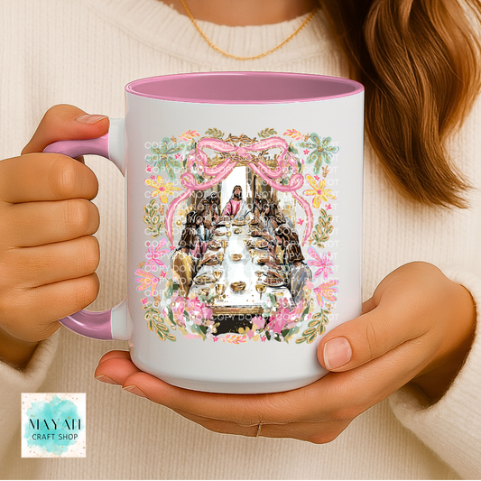 Person holding a mug with decorative design, featuring a pink interior and handle.