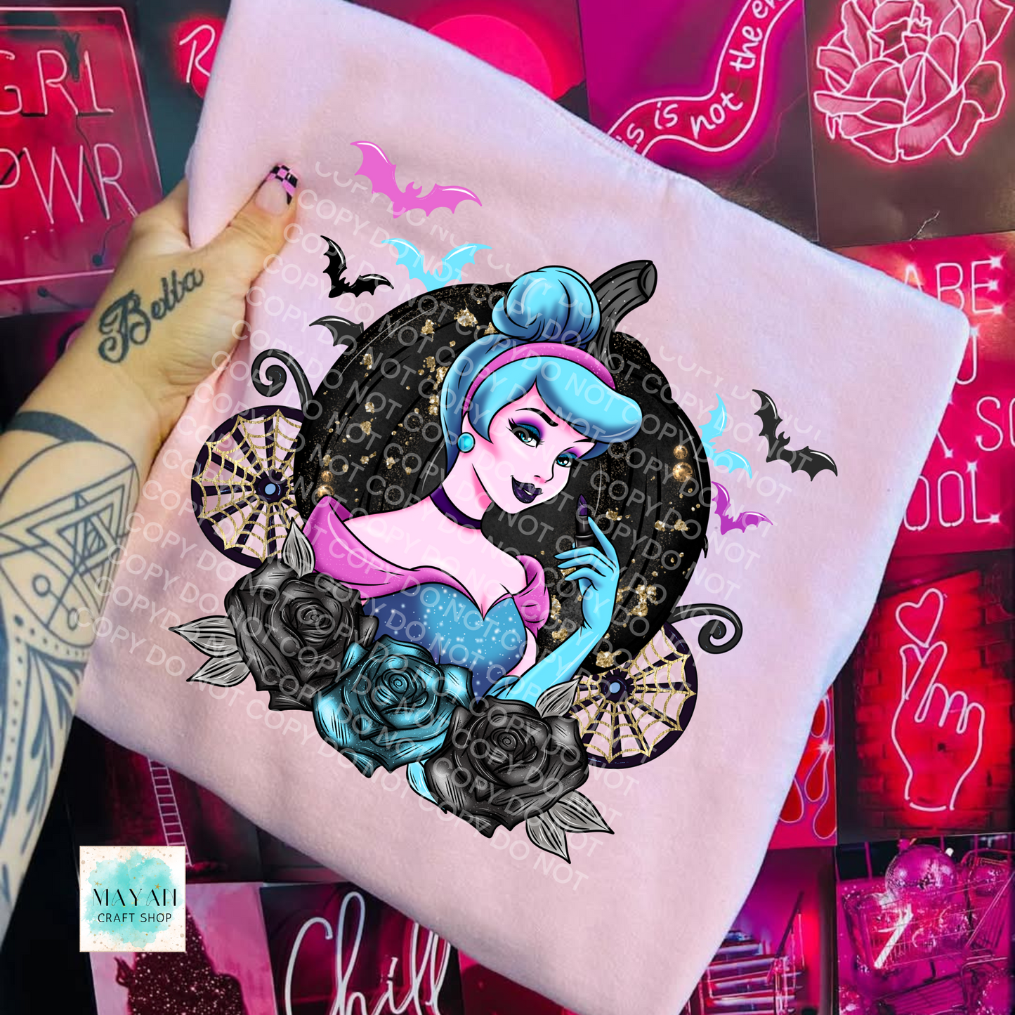 Hand holding a shirt with a stylized character design against a neon sign background