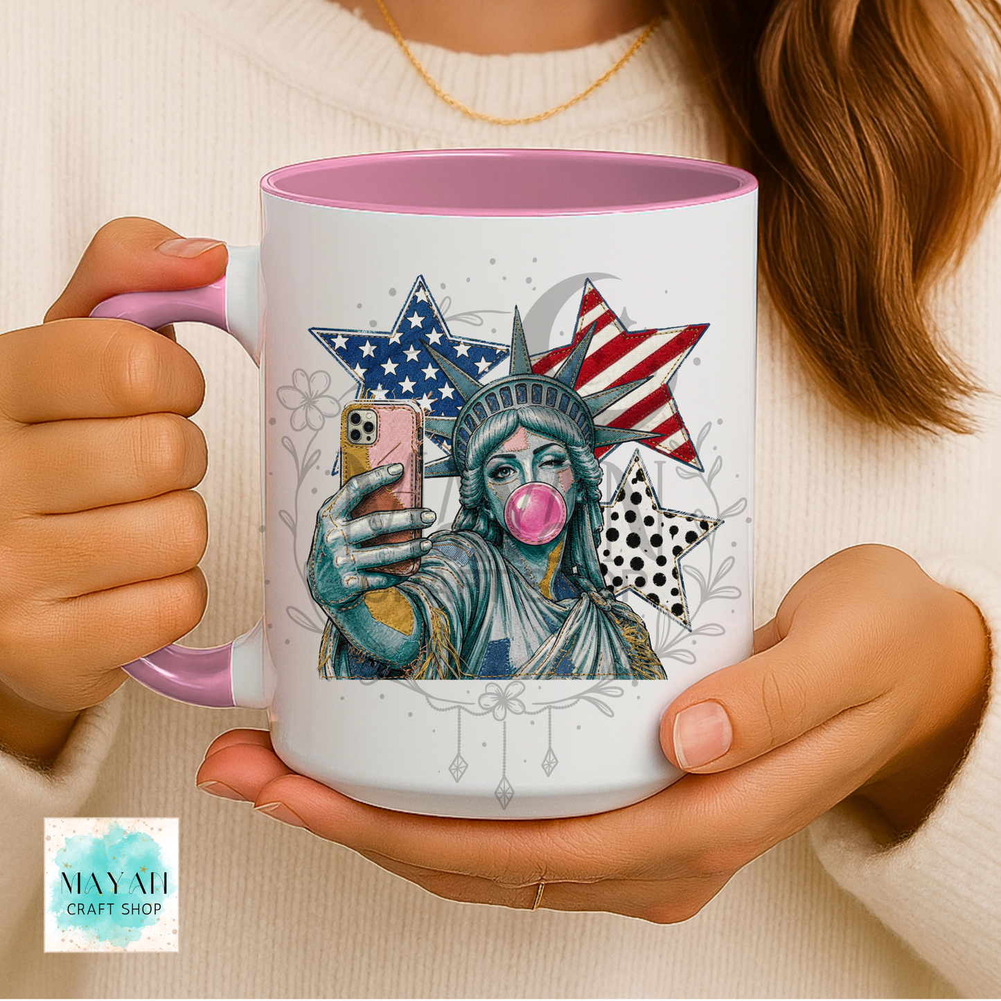 Person holding a mug with a colorful design of the Statue of Liberty taking a selfie.