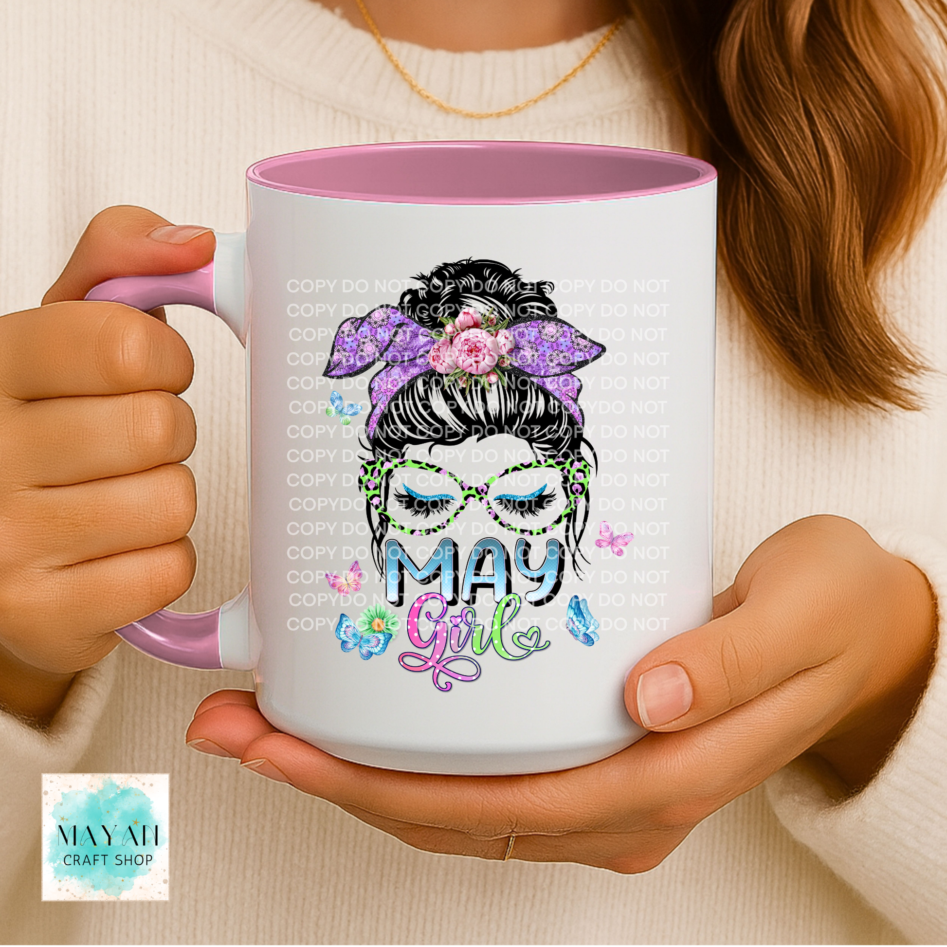 Person holding a mug with 'May Girl' design and pink handle.