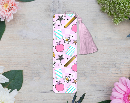 Pink bookmark with tassel on a wooden surface with flowers
