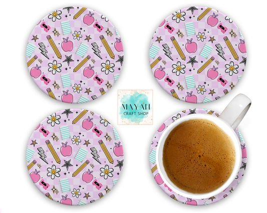 Set of four pink coasters with stationery-themed design, one coaster with a cup of coffee.