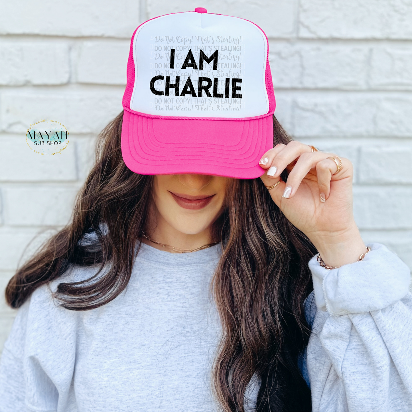 Person wearing a pink and white cap with 'I AM CHARLIE' text against a light-colored wall.