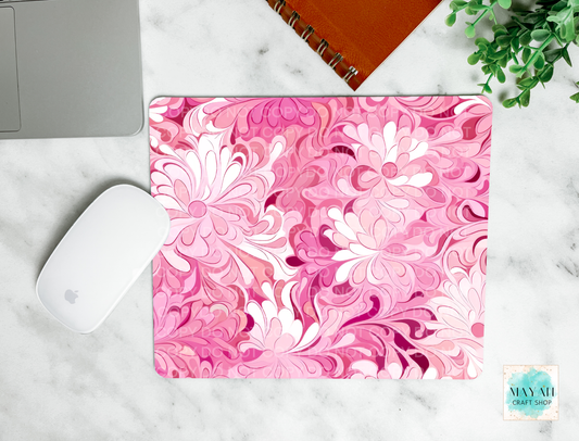 Pink floral mouse pad on a marble surface with a laptop and mouse.