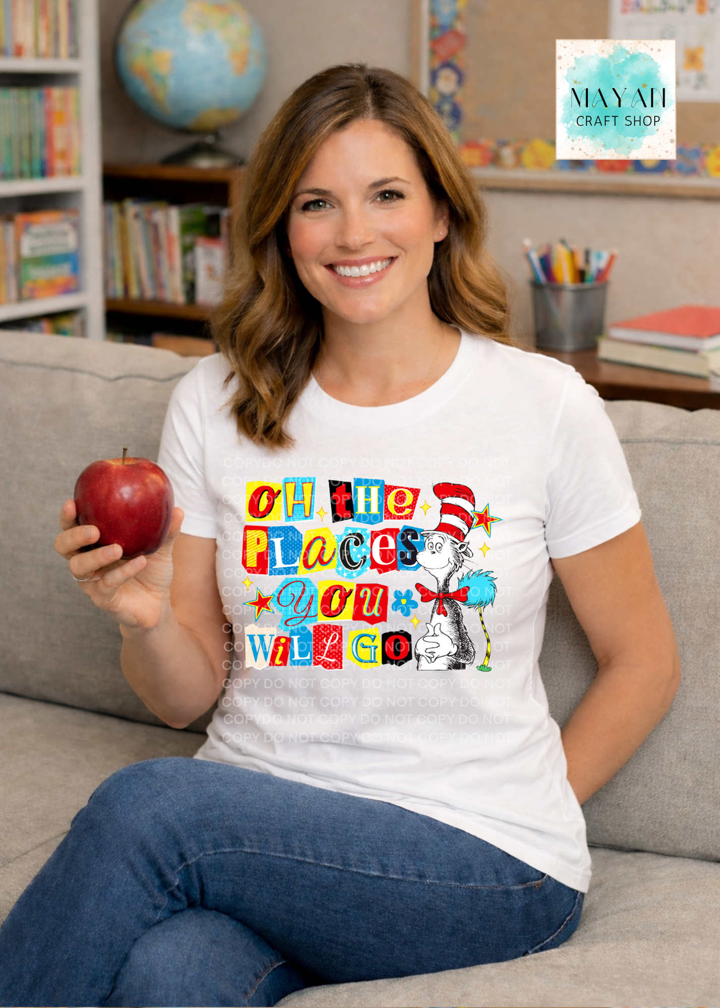 Woman wearing a t-shirt with a colorful design, holding an apple, sitting on a couch in a classroom setting.
