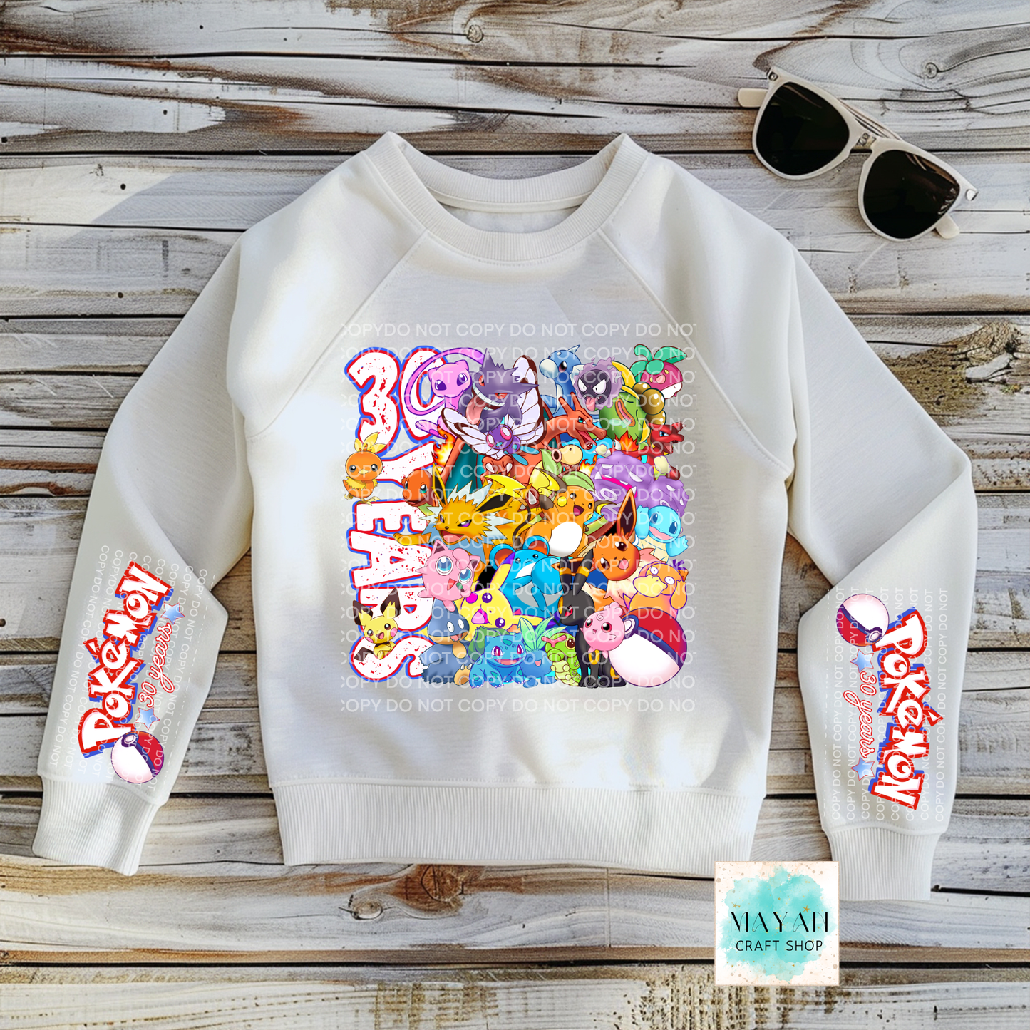 White sweatshirt with colorful design on a wooden surface, with sunglasses and a tag visible.