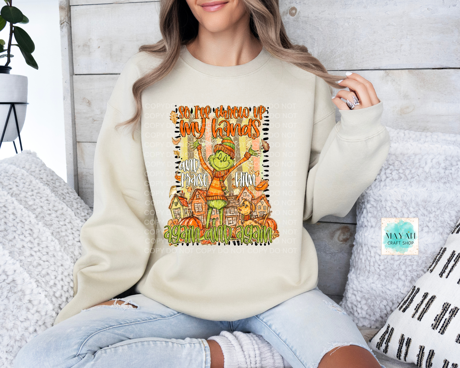 Person wearing a cream sweatshirt with a colorful graphic design, sitting on a wooden floor.