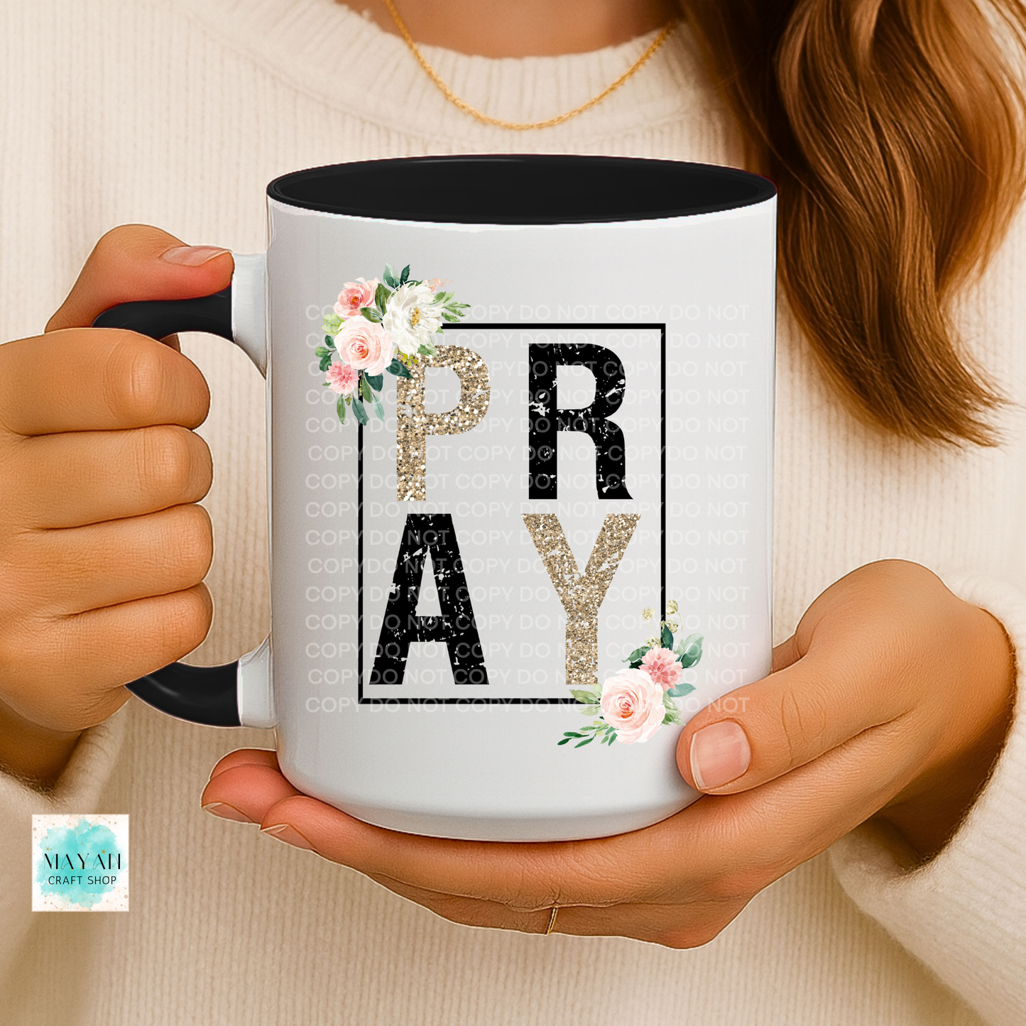 Person holding a mug with 'PRAY' text and floral designs.