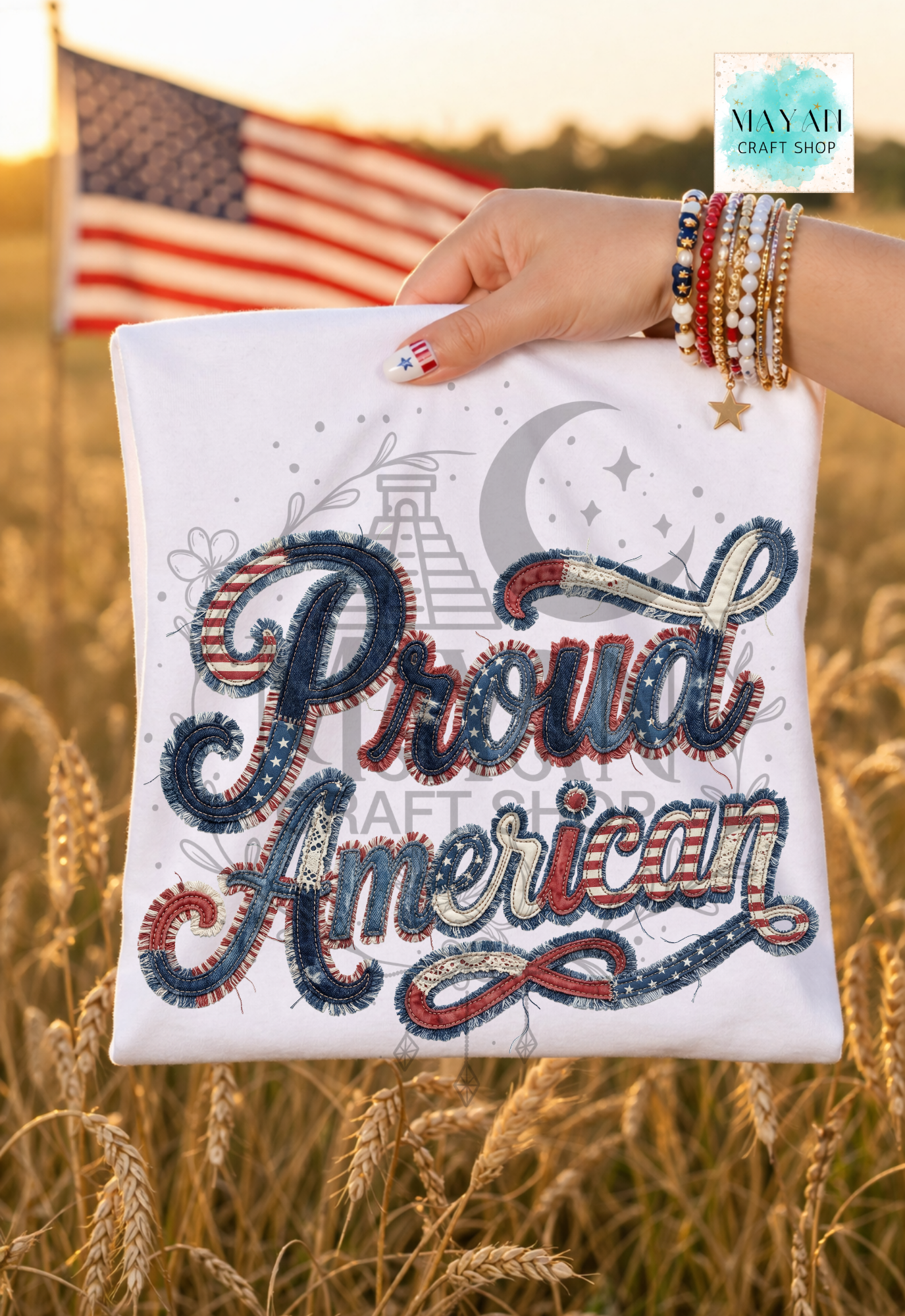 Hand holding a white pillow with 'Proud American' text against an American flag and sunset background.