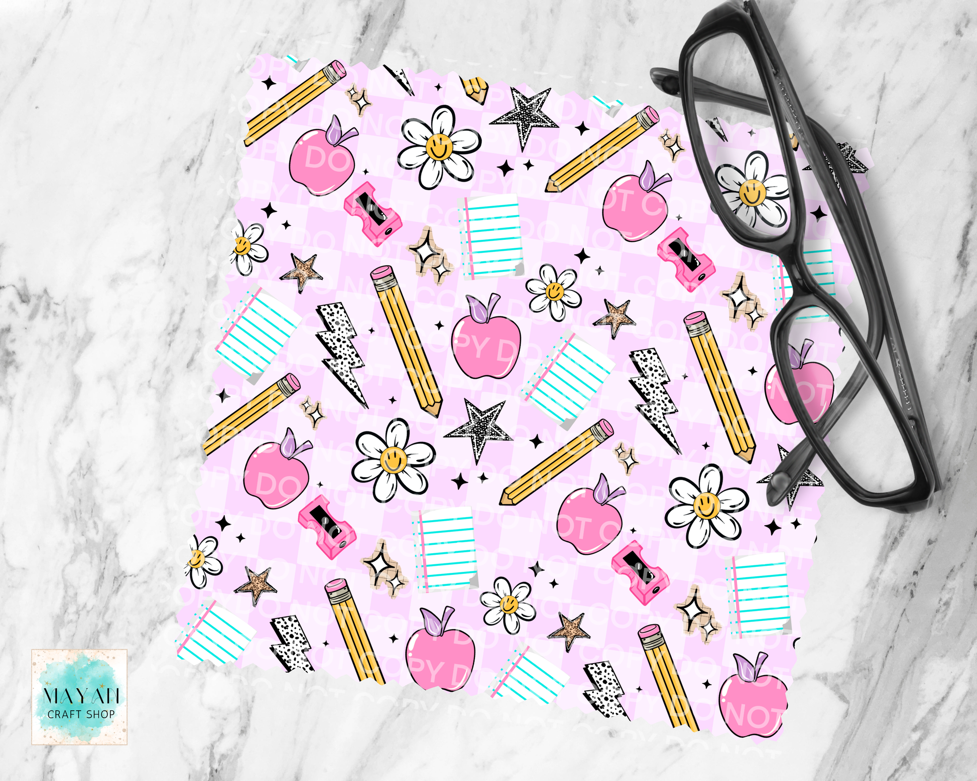 Pink patterned product with school-themed elements on a marble surface, featuring a pair of glasses.