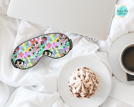 Sleep mask with cartoon design on a white surface with a plate of food and coffee.