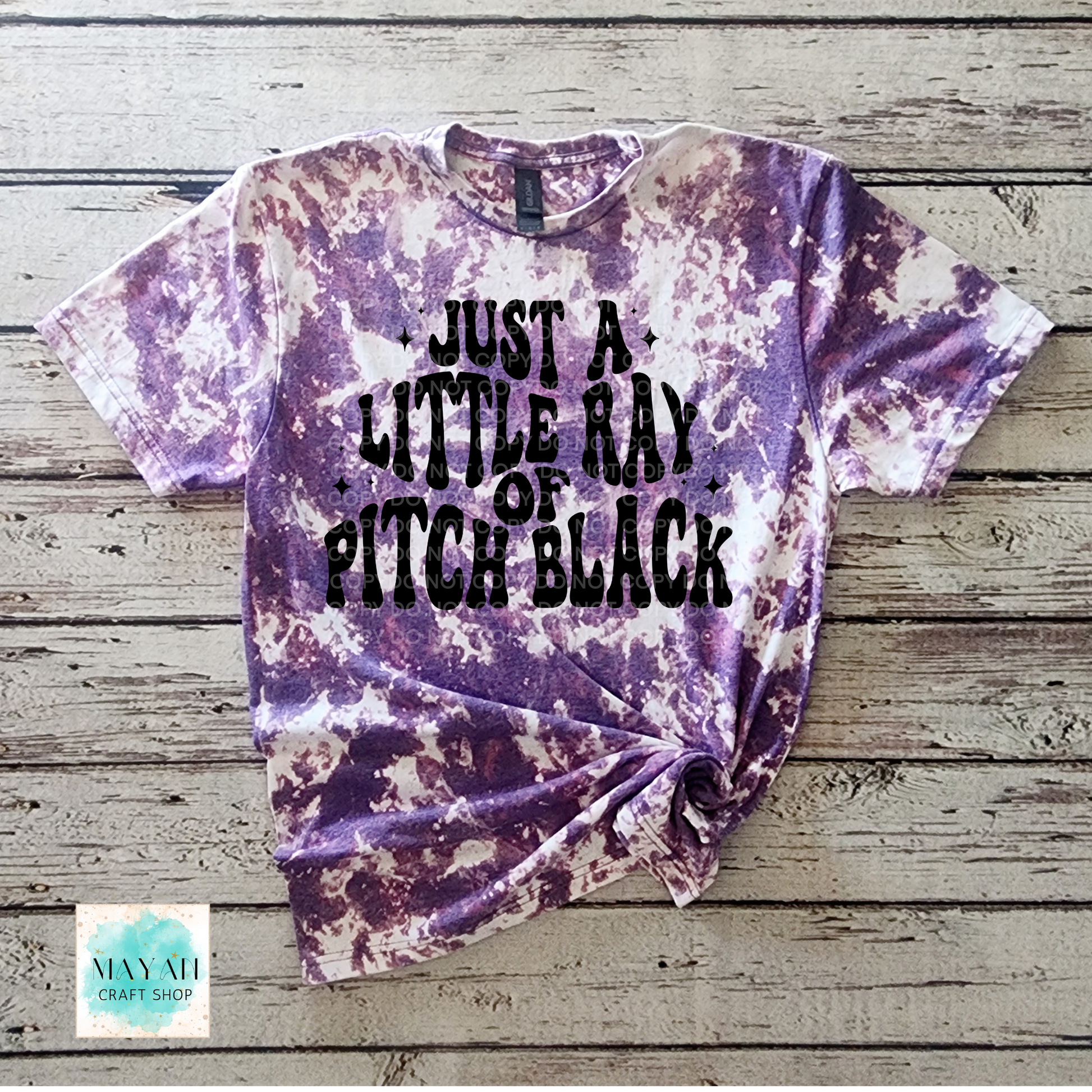 Bleached t-shirt with text on a wooden surface, featuring the brand 'Mayan Craft Shop'.