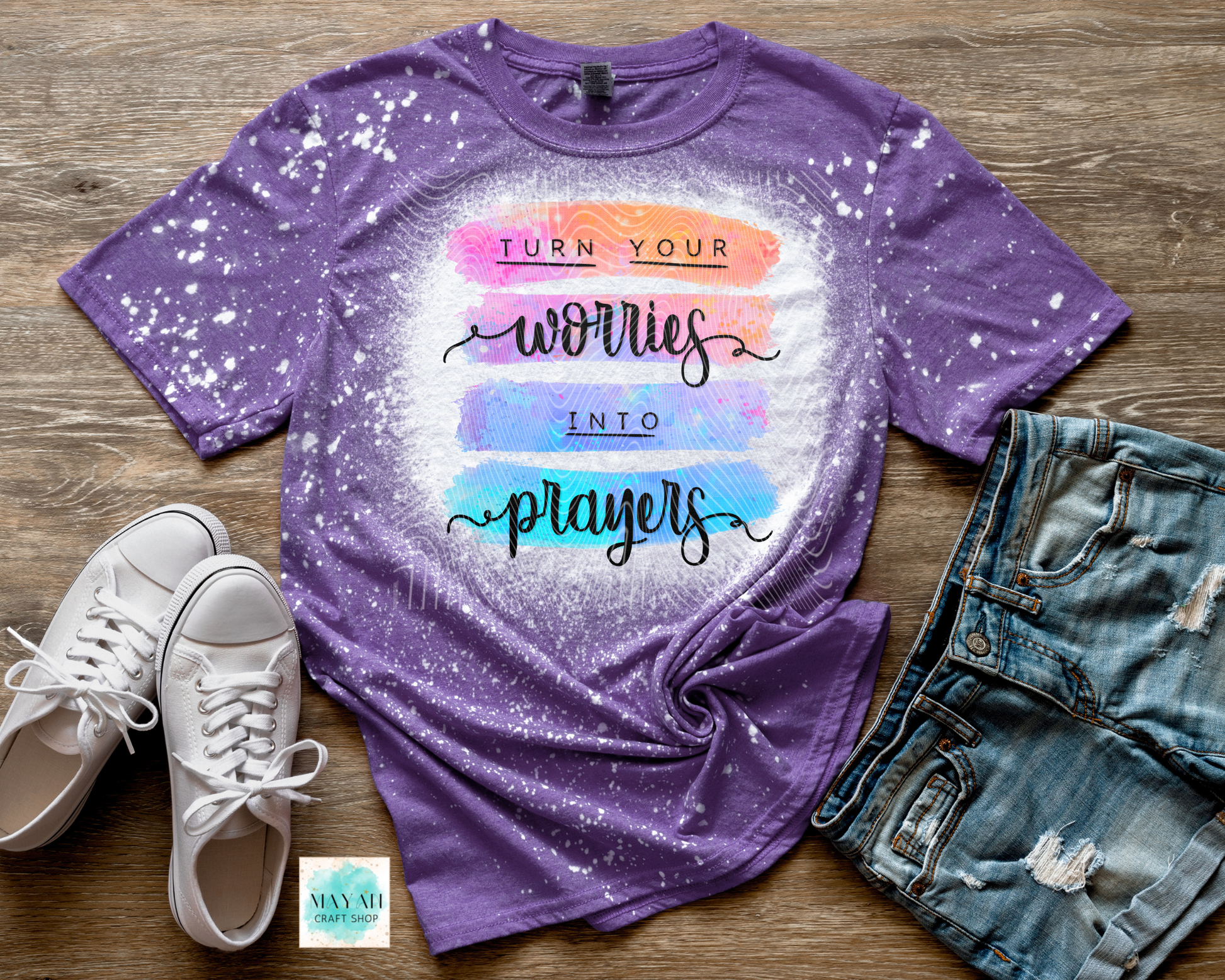 Purple t-shirt with motivational quote on a wooden surface with shoes and jeans.