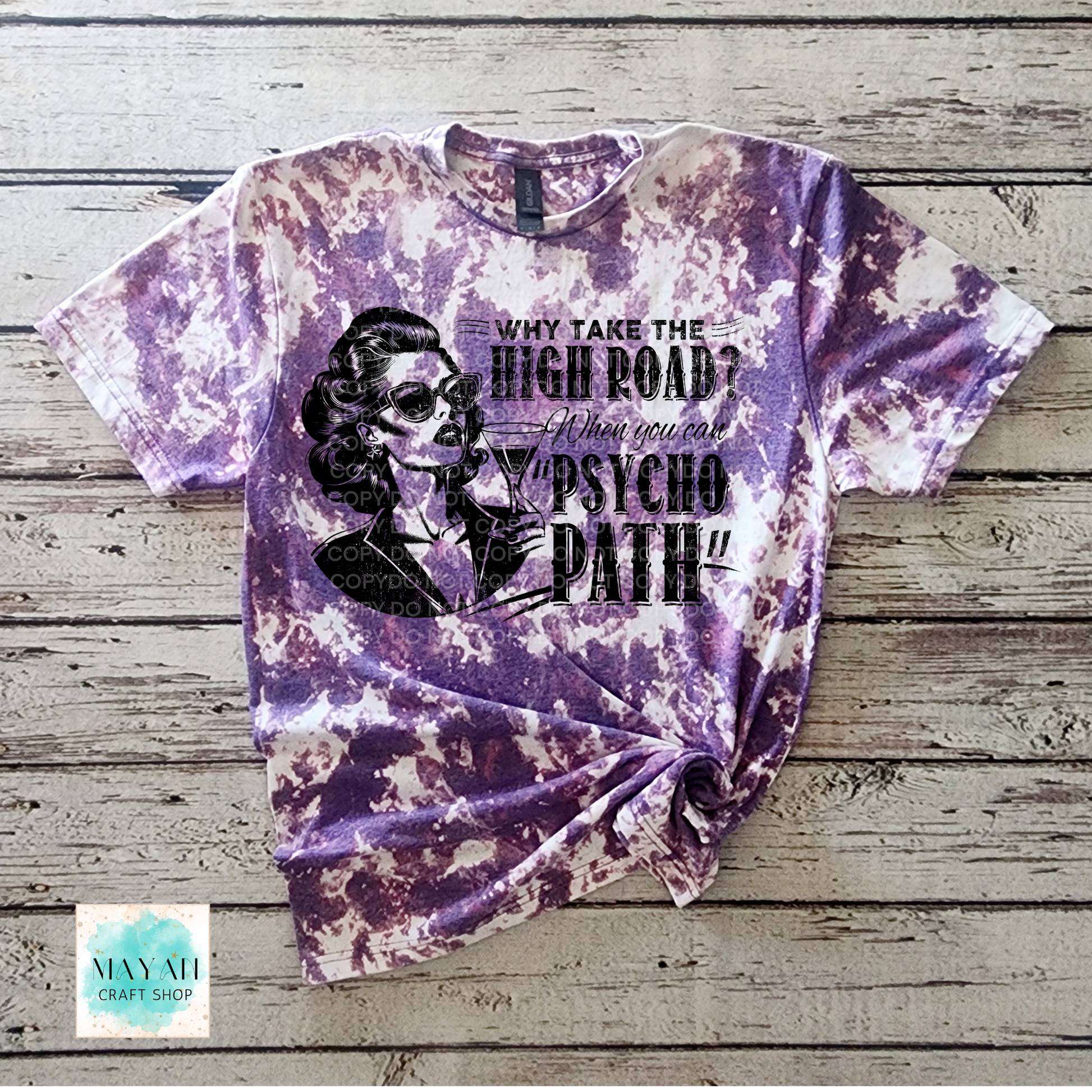 Purple tie-dye t-shirt with graphic design and text on a wooden surface