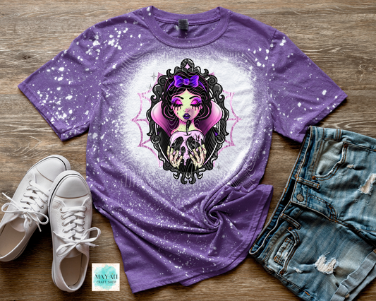 Purple t-shirt with graphic design on a wooden surface with shoes and jeans.
