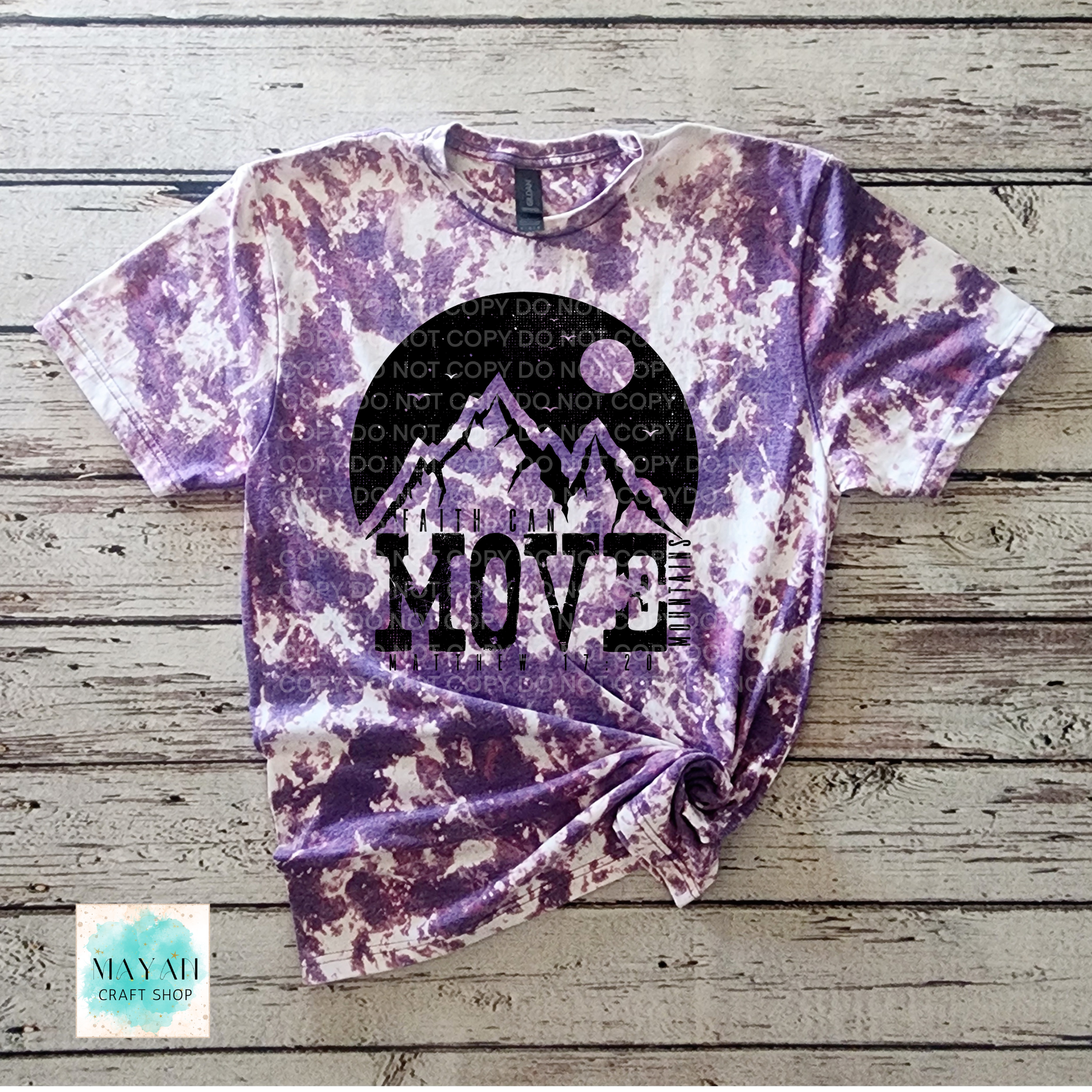 Tie-dye t-shirt with mountain design and 'MOVE' text on a wooden surface, featuring a watermark.