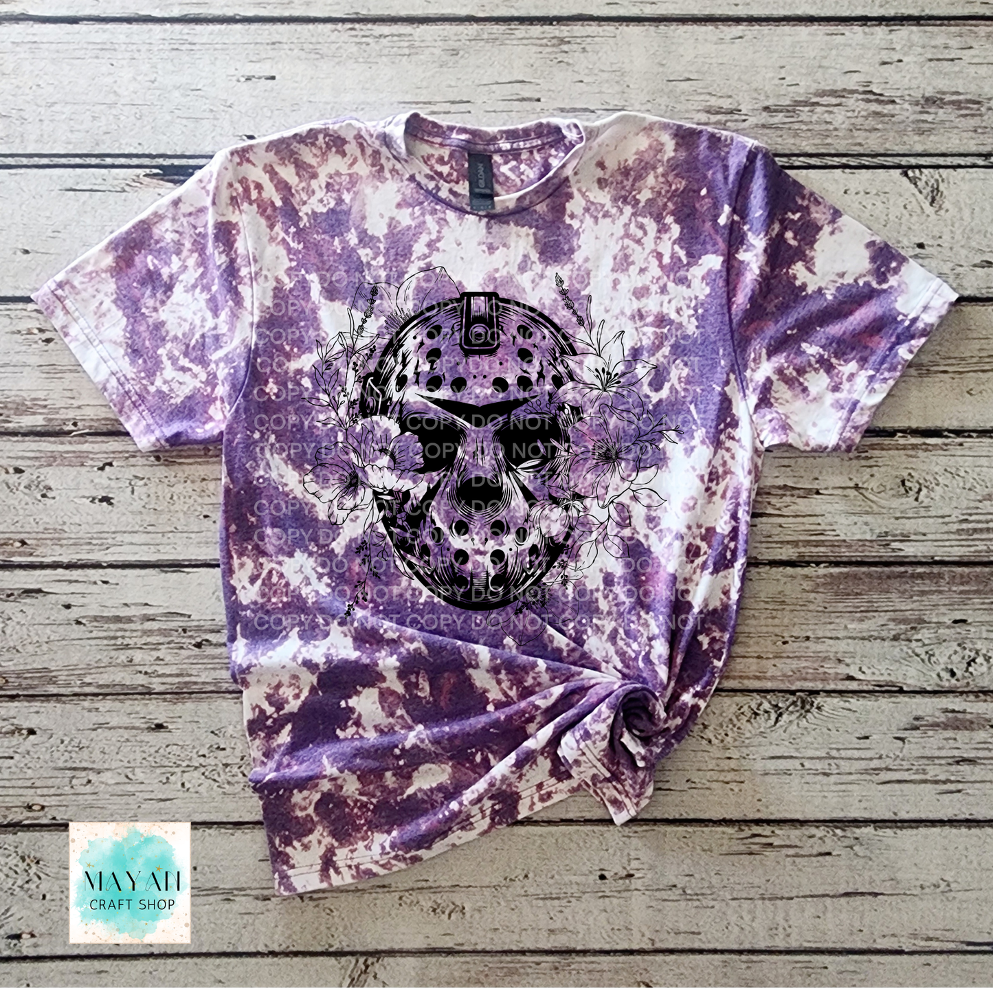 Tie-dye t-shirt with a skull design on a wooden surface, featuring the brand.