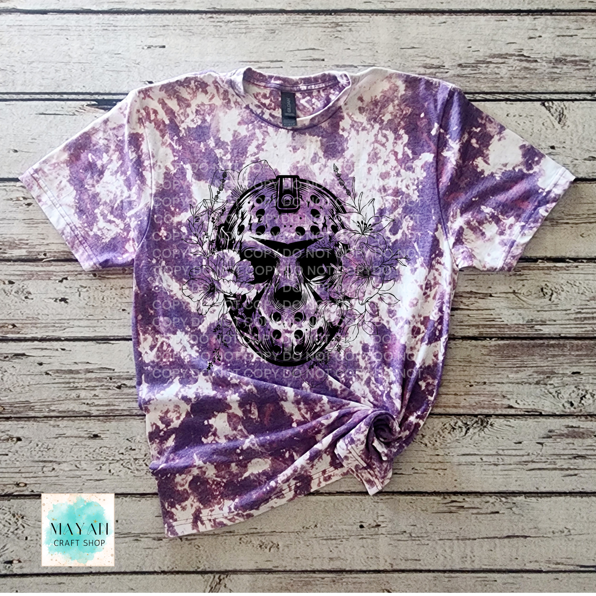 Tie-dye t-shirt with a skull design on a wooden surface, featuring the brand.