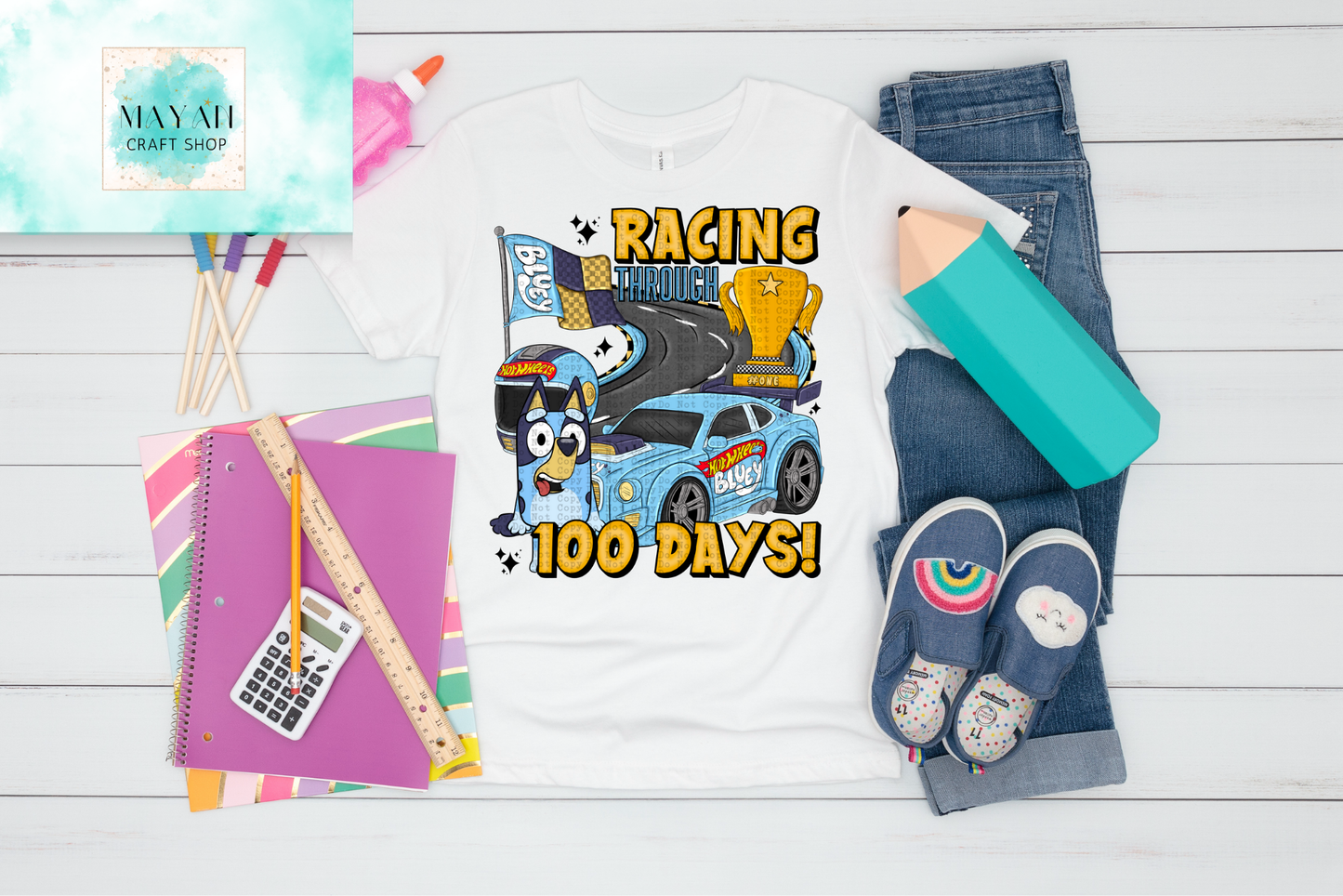 T-shirt with dog design, notebook, ruler, and shoes on a wooden surface