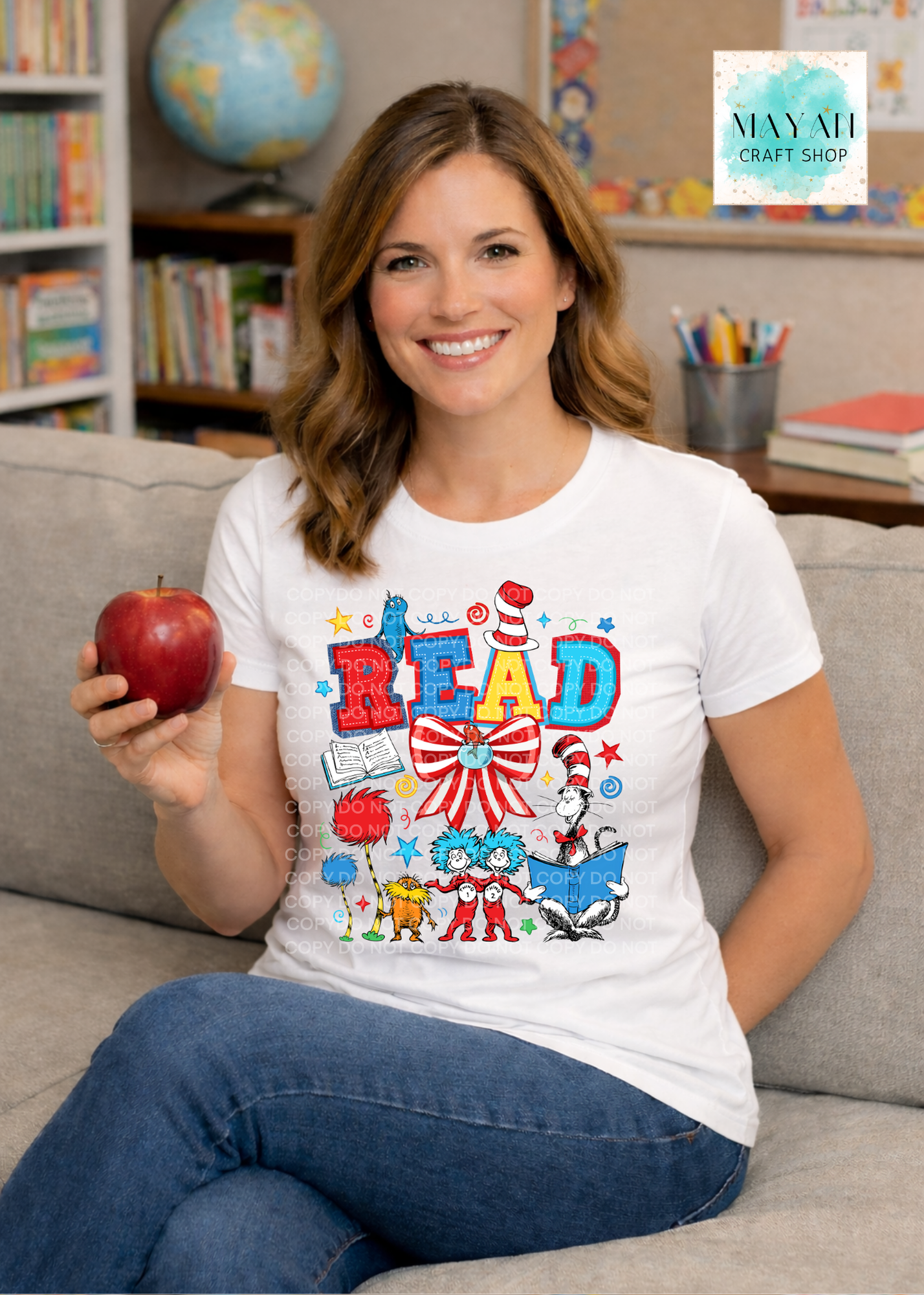 Woman wearing a 'READ' t-shirt with cartoon characters, holding an apple in a classroom setting.