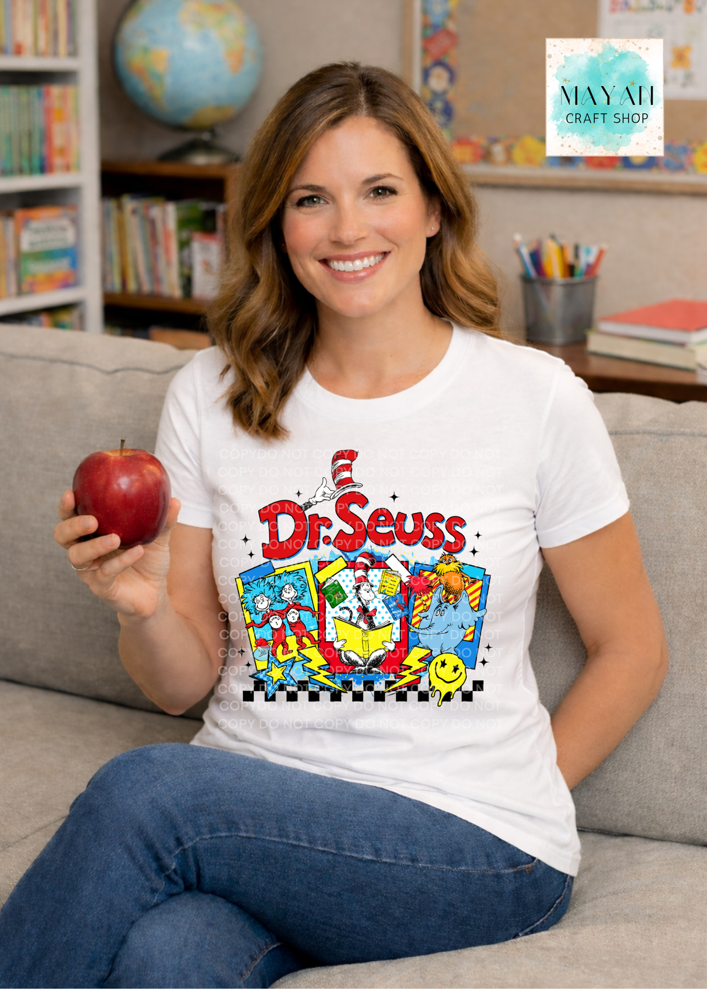 Woman wearing a reading cat t-shirt holding an apple in a classroom setting.
