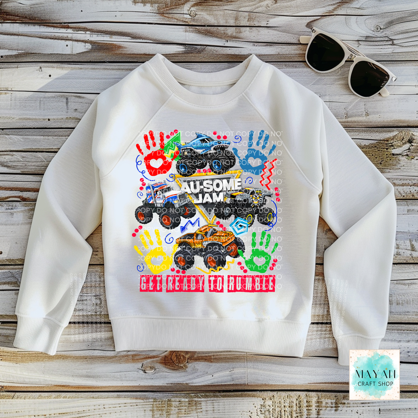 White sweatshirt with colorful monster truck design on a wooden surface