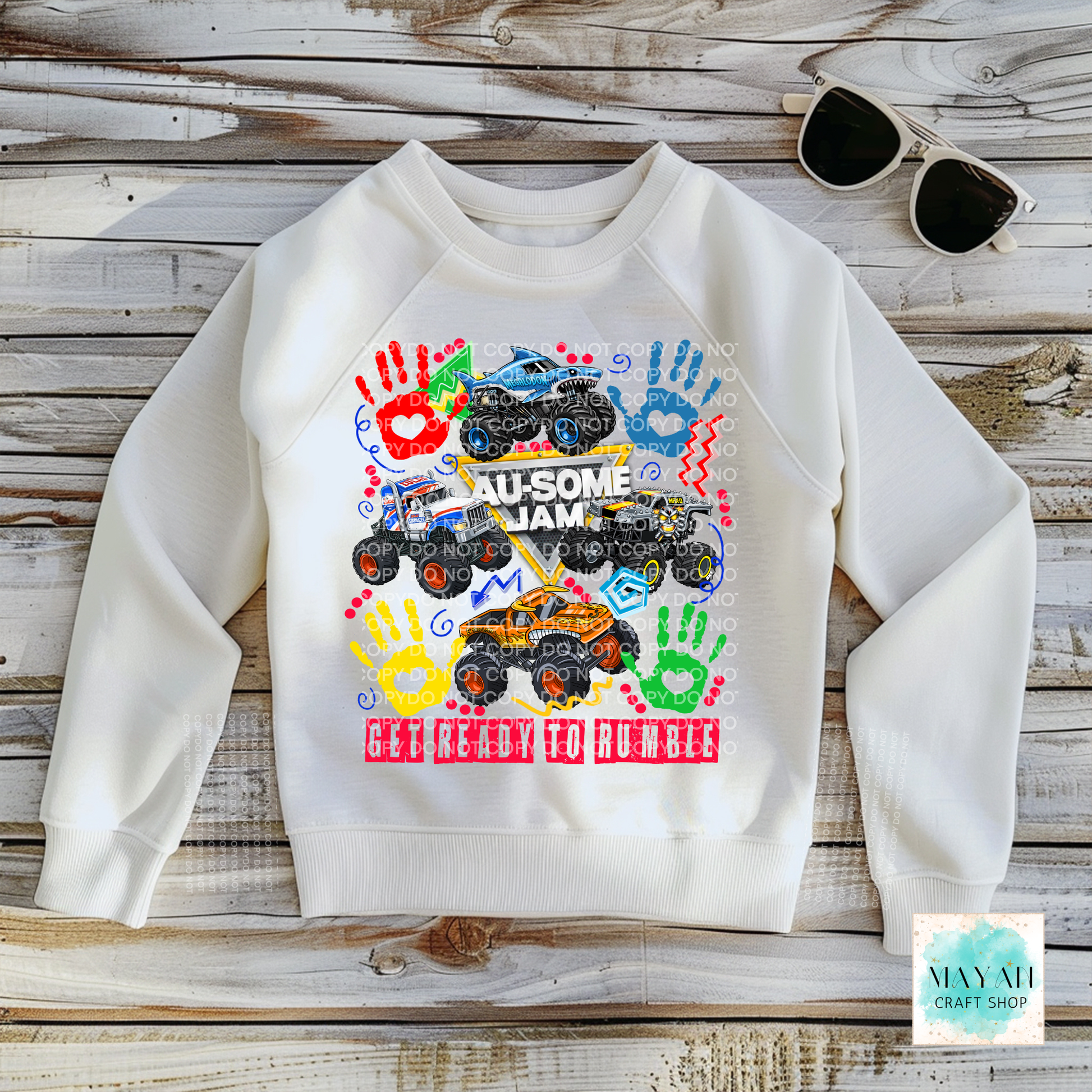 White sweatshirt with colorful monster truck design on a wooden surface