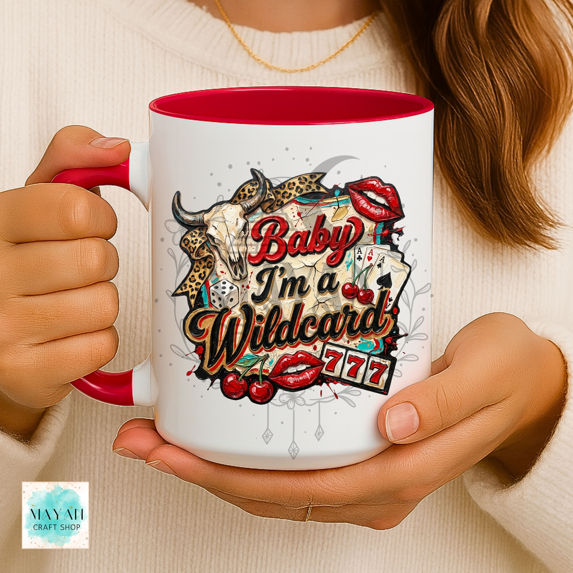 Person holding a mug with a colorful design and text, featuring a red interior.