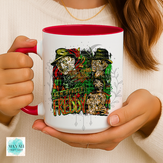 A person holding a white ceramic mug with a red interior and handle. The mug features a graphic print of three faces with a text.